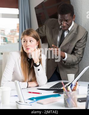 Un patron d'homme malheureux qui a colludé des erreurs dans le travail à la jeune femme gestionnaire Banque D'Images