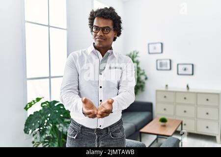 Psychologue africain au bureau de consultation souriant avec les mains paumes ensemble recevoir ou donner le geste. Tenir et la protection Banque D'Images
