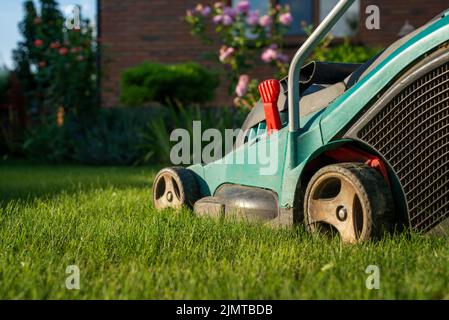 Motionnaire de pelouse sur l'herbe verte dans la maison en brique et en avant Banque D'Images