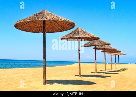 Rangée de parasols en bois à la plage de sable, mer Banque D'Images