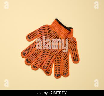 Gants de travail en tissu orange sur fond jaune. Banque D'Images