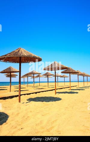 Rangée de parasols en bois à la plage de sable, mer Banque D'Images