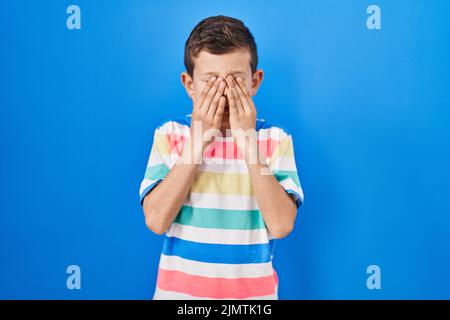 Jeune caucasien debout sur fond bleu yeux frottant pour la fatigue et les maux de tête, l'expression endormi et fatigué. Problème de vision Banque D'Images