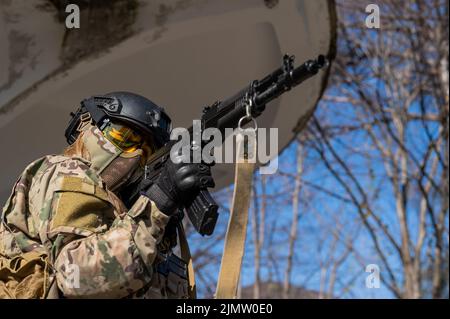 Portrait d'une femme dans un casque et des lunettes avec une mitrailleuse dans les mains. Une femme soldat en uniforme de camouflage tient une arme. Banque D'Images