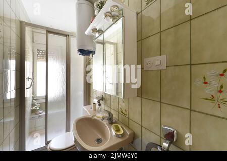 Salle de bains avec murs carrelés, meuble-lavabo en porcelaine et cabine de douche à panneaux de verre Banque D'Images