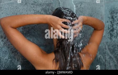 Vue arrière de la jeune femme caucasienne prenant une douche dans la salle de bains à la maison Banque D'Images