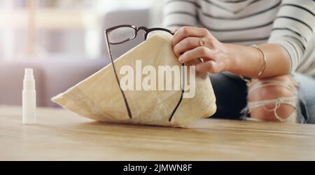 Apprenez à nettoyer vos lunettes sans les endommager. Une femme méconnaissable nettoie ses lunettes de lecture à la maison. Banque D'Images