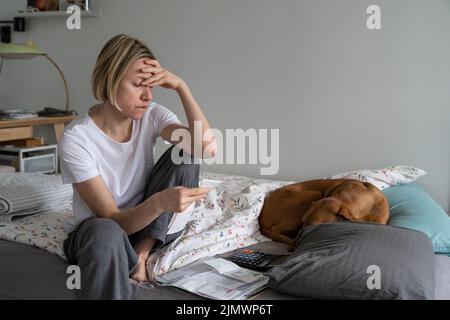Une seule femme d'âge moyen s'assoit au lit et regrette d'avoir augmenté le coût de la vie en gros plan Banque D'Images