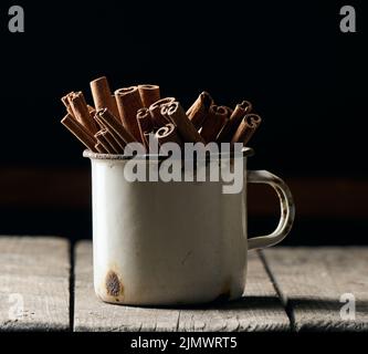 Bâtonnets de cannelle brun sec dans une vieille tasse en métal, épice culinaire Banque D'Images