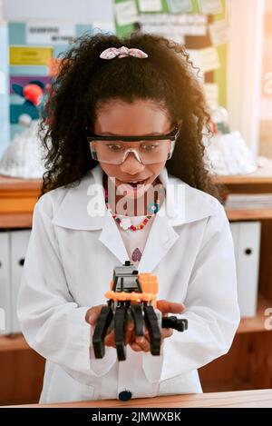 L'avenir appartient aux curieux. Une adorable petite fille construisant un robot en classe de sciences à l'école. Banque D'Images