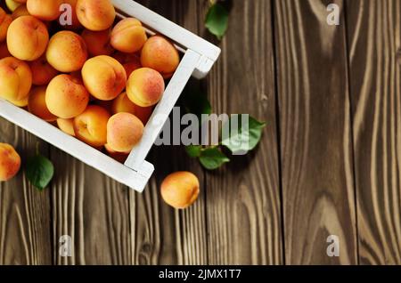 Caisse en bois blanc avec des abricots sur table. Vue d'en haut. Banque D'Images