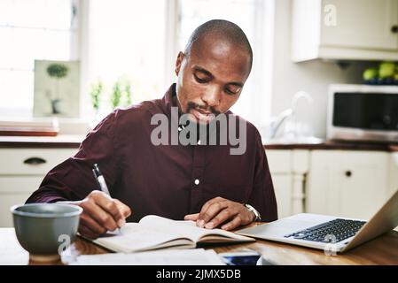 Votre éthique professionnelle vous parle beaucoup de vous dans les affaires. Un beau homme qui passe par la paperasse et utilise son ordinateur portable tout en travaillant à la maison pendant la journée. Banque D'Images