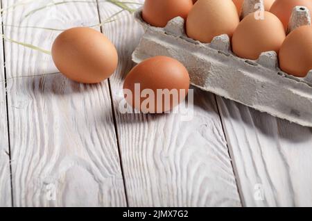 Brown biologiques crus les oeufs de poule en papier sur carton écologique cuisine blanc table en bois Banque D'Images