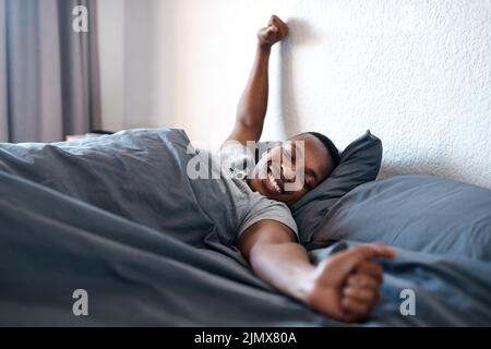Je suis amoureux de mon lit. Un beau jeune homme allongé dans le lit seul et s'étirant pendant une journée de congé à la maison. Banque D'Images