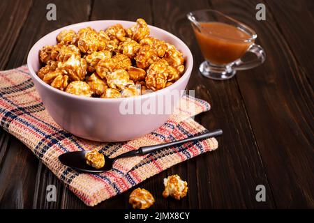 Bol en argile avec pop-corn au caramel sur fond de bois Banque D'Images