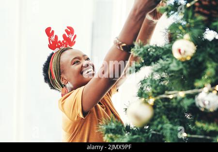 Rien ne vous obtient dans l'esprit comme la décoration de l'arbre. Une jeune femme d'affaires attrayante décorant un arbre de Noël dans son bureau au travail. Banque D'Images