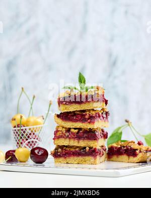 Des tranches carrées de crumble de cerise se trouvent dans une pile sur un tableau blanc Banque D'Images