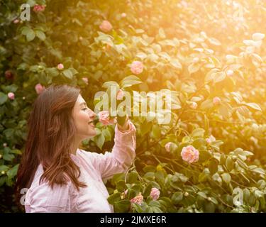 Belle femme heureuse tenant une fleur rose croissance vert branche Banque D'Images