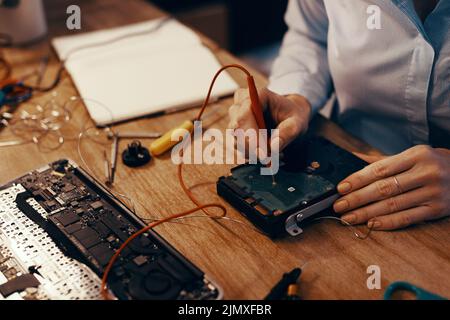 Shell enregistre vos informations. Une femme informacienne méconnaissable répare un disque dur dans son atelier. Banque D'Images