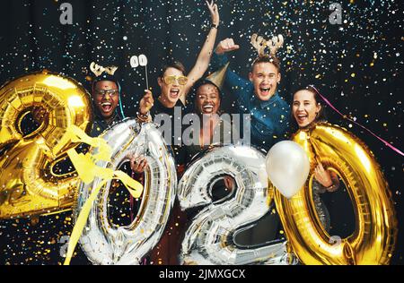 Nous n'avons jamais été aussi enthousiastes pour une nouvelle année. Portrait rogné d'un groupe diversifié d'amis debout ensemble et célébrant le nouvel an en soirée Banque D'Images