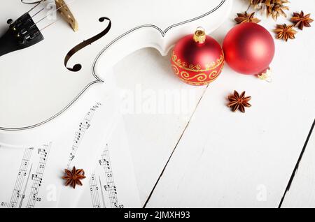 Fermer la vue d'un violon rouge notes de musique et des boules de décoration de Noël sur table en bois blanc Banque D'Images