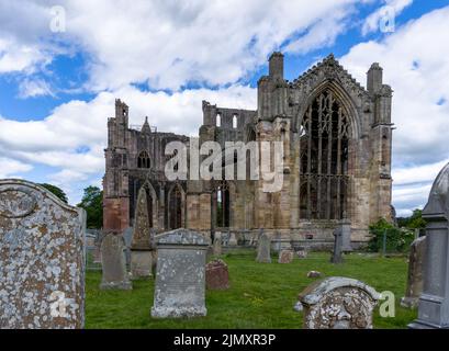 Vue sur les ruines de l'abbaye de Melrose et les pierres à tête historiques dans le cimetière de l'église Banque D'Images