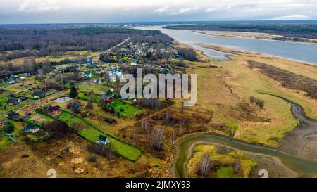 Vue aérienne du village sur une haute colline au-dessus de la rivière au lever du soleil en automne. Vue aérienne. Bâtiments résidentiels et une église, virages de rivière, prés, Banque D'Images