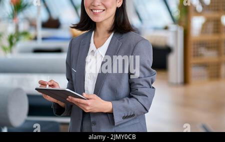 Jeune femme d'affaires asiatique souriante utilisant une tablette numérique, gros plan. Banque D'Images