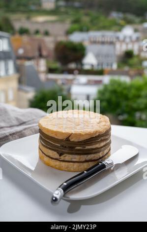 Dégustation de fromage de vache livarot jaune de Lisieux, région du Calvados et vue sur les maisons anciennes d'Etretat, Normandie, France Banque D'Images