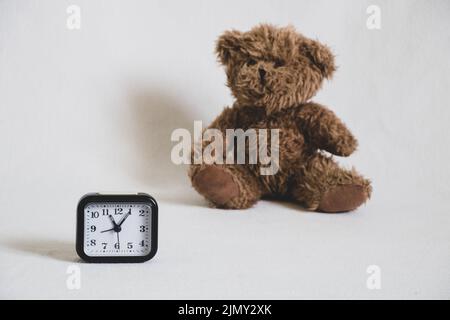 ours en peluche pour enfants et horloge sur fond blanc, réveil sur table Banque D'Images