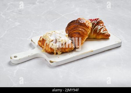 Assortiment de croissants frais sur plateau de service blanc sur fond de marbre Banque D'Images