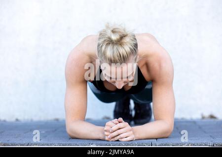 Belle femme sportive se concentrant dans la salle de gym tout en faisant des exercices de remise en forme. Jeune blonde en forme parfaite faisant planche Banque D'Images