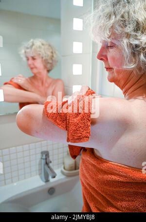 Une femme se lavant avec un flanelle et du savon au lavabo de la salle de bains pour économiser de l'eau car certaines régions de la Grande-Bretagne connaissent des pénuries d'eau Banque D'Images