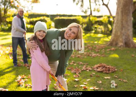 Image de la grand-mère et de la petite-fille du caucase qui balaie les feuilles dans le jardin Banque D'Images