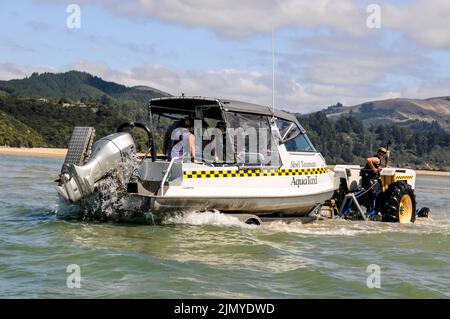 Un bateau-taxi touristique est remorqué dans la mer de Tasman par un tracteur à Marahau, sur l'île du Sud, en Nouvelle-Zélande Banque D'Images