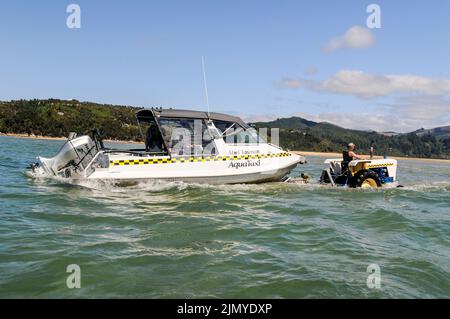 Un bateau-taxi touristique est remorqué dans la mer de Tasman par un tracteur à Marahau, sur l'île du Sud, en Nouvelle-Zélande Banque D'Images