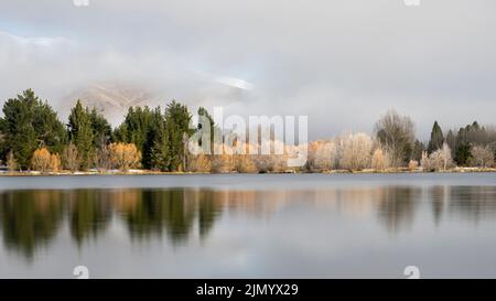 Soulèvement de brouillard au-dessus du bras Wairepo du lac Ruatuniwha, fusion du givre de houar reflété dans le lac, Twizel, Canterbury. Banque D'Images