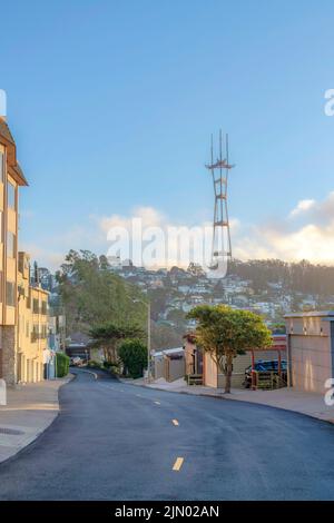 Vue sur le quartier résidentiel incliné en dessous de la tour Sutro à San Francisco, CA. Il y a des maisons des deux côtés de la route vide avec des arbres et des lig de rue Banque D'Images