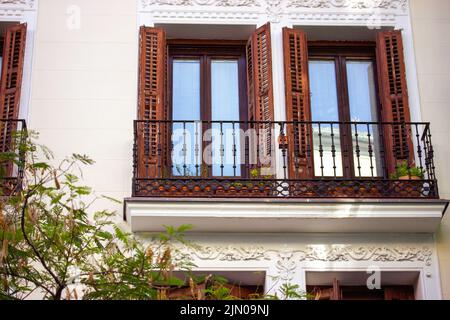 Madrid, Espagne. 3 juillet 2022 Une belle façade en stuc de maison blanche résidentielle, bâtiment, balcon, baies vitrées avec volet en bois ouvert Banque D'Images