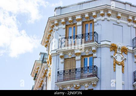 Madrid, Espagne. 1 juin 2022. Coin d'un beau bâtiment résidentiel historique avec une façade gris-bleu joliment décorée, fenêtres avec shu en bois Banque D'Images