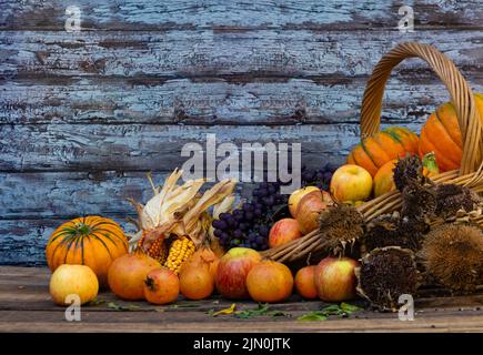 panier rempli de citrouilles, de pommes et de divers fruits et fleurs d'automne Banque D'Images