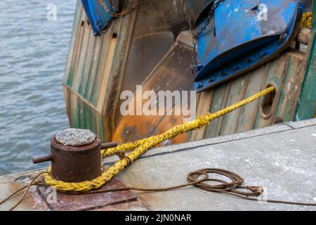 Bollard avec corde jaune et bateau de pêche dans le nord des pays-Bas Banque D'Images