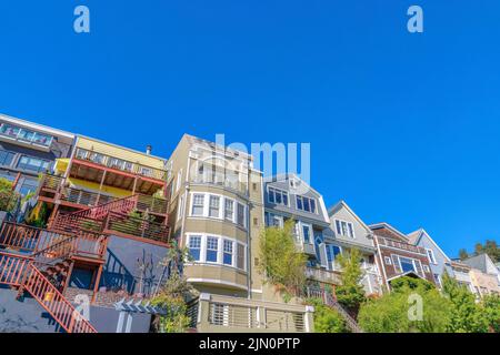 Façade de maisons de quatre étages avec escaliers à l'entrée et balcons à San Francisco, CA. Rangée de maisons dans une vue à angle bas avec des panneaux latéraux en bois et t Banque D'Images