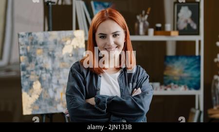 Portrait gros plan femelle heureux peintre art étudiant université fille artiste avec cheveux rouges talentueux créateur artiste artiste femme posant croisant Banque D'Images
