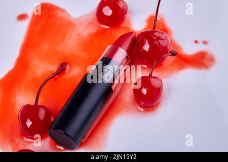 Gros plan sur le rouge à lèvres et les cerises sur la tache. Isolé sur blanc. Banque D'Images