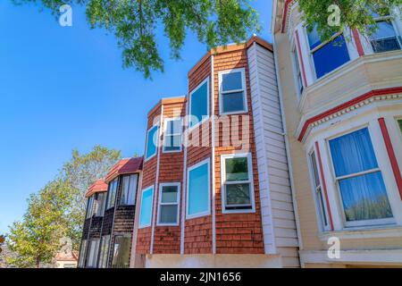 Fenêtres de baie d'une maison adjacente avec des sidings de bois à San Francisco, Californie. Vue latérale des maisons avec panneaux de verre réfléchissants contre le Banque D'Images