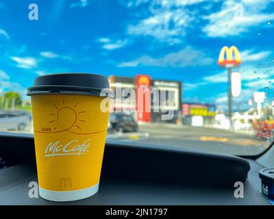 Tasse de café McCafe Japan jaune sur le tableau de bord d'une voiture achetée au service au drive de McDonald's. Banque D'Images