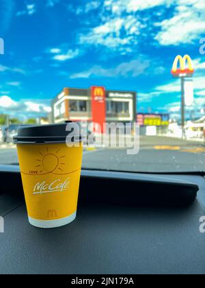 Tasse de café McCafe Japan jaune sur le tableau de bord d'une voiture achetée au service au drive de McDonald's. Banque D'Images