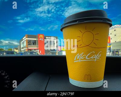 Tasse de café McCafe Japan jaune sur le tableau de bord d'une voiture achetée au service au drive de McDonald's. Banque D'Images