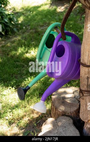 Vieux arrosoirs en plastique pour arroser les fleurs dans le jardin. Banque D'Images